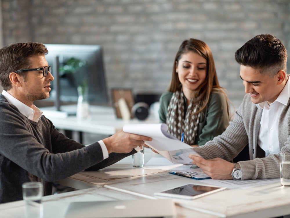 happy couple signing contract meeting with their real estate agent office