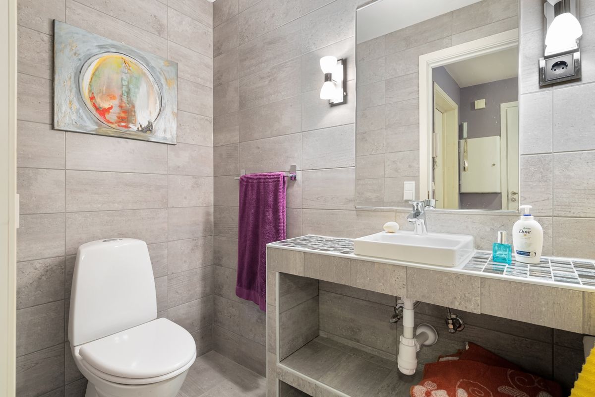 Nhà vệ sinh ốp gạch xám với bồn cầu và lavabo